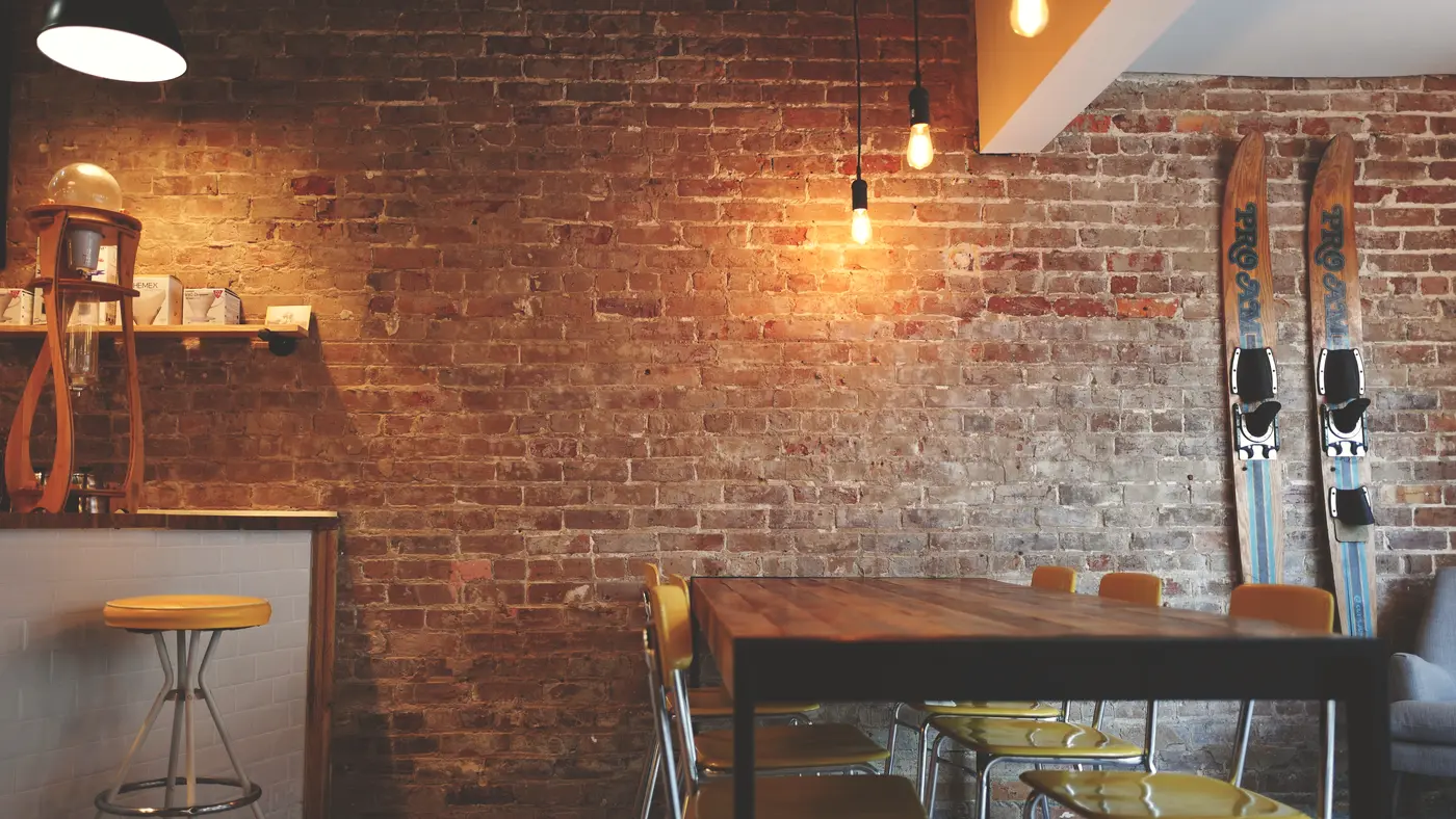 Empty cafe interior with brick wall, wooden table and stools