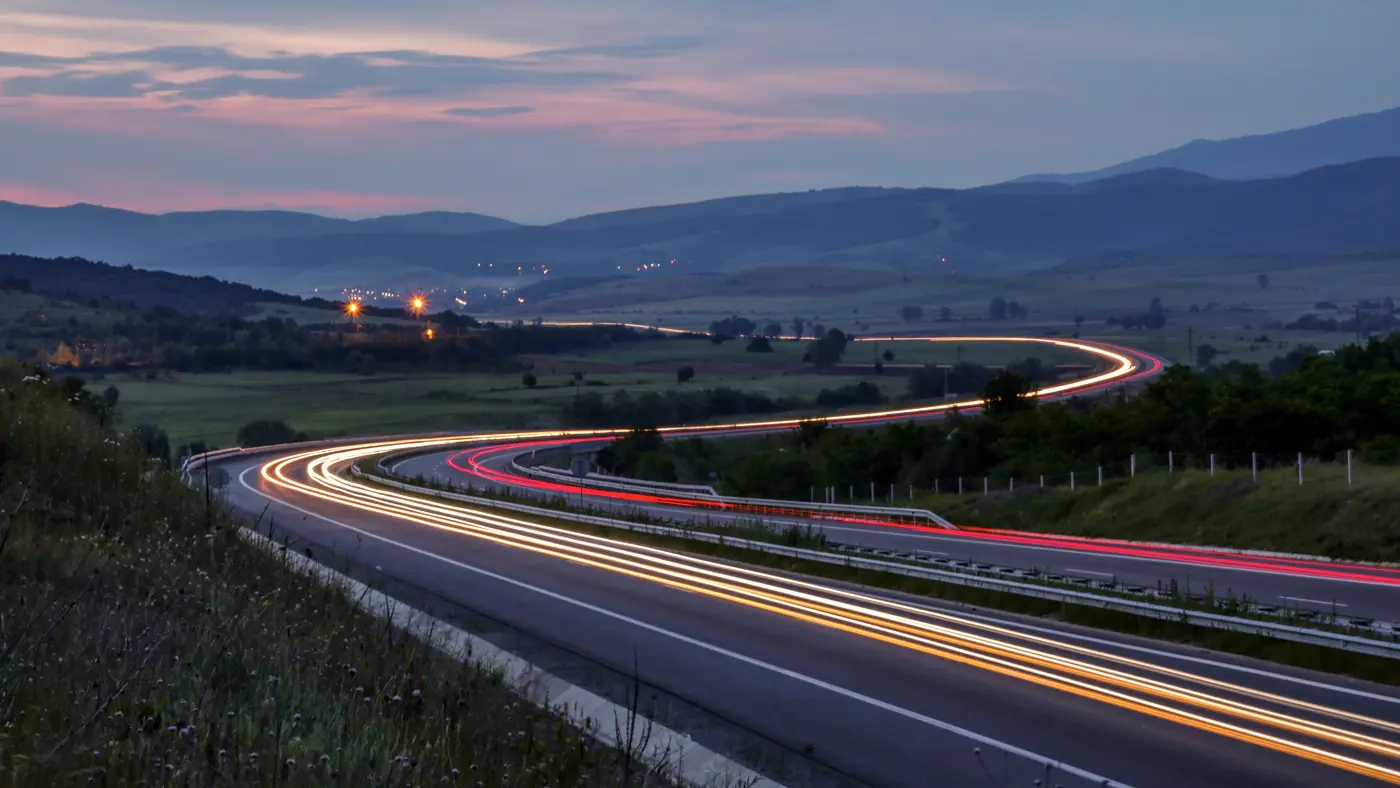Car light trails on a curving highway at dusk