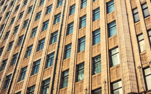 Sandstone office building facade with rows of tall windows