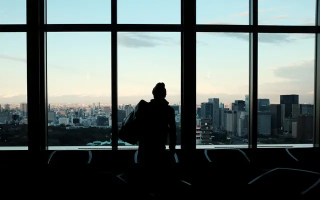 Silhouette of a person at an office window above a city skyline